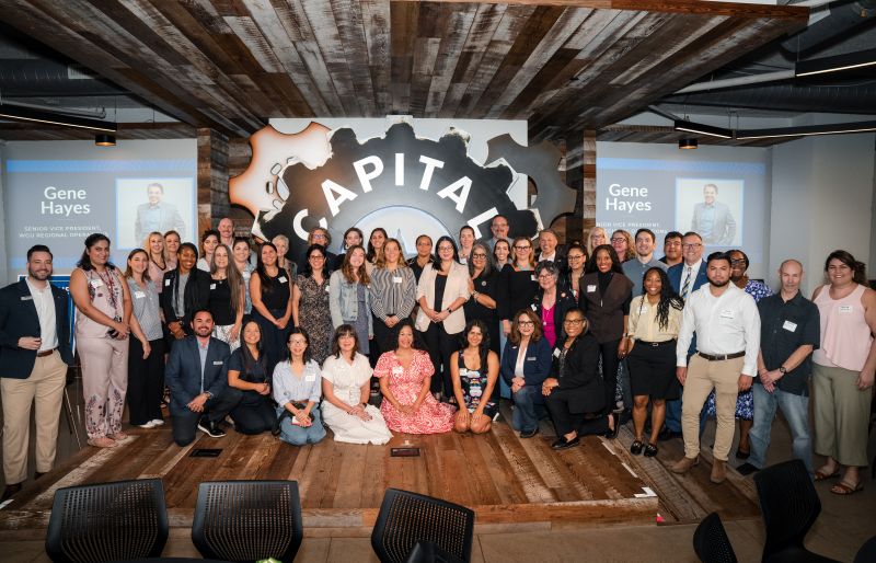 Group photo of over forty professionals dressed in business casual.